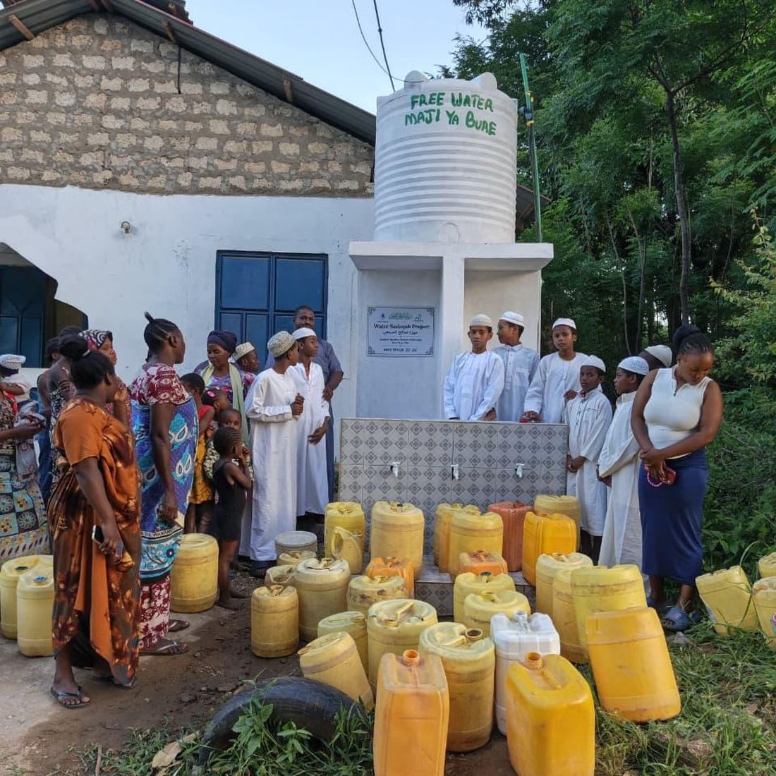 Villagers and children with jerrycans around the finished water tank in Bondeni, Kenya