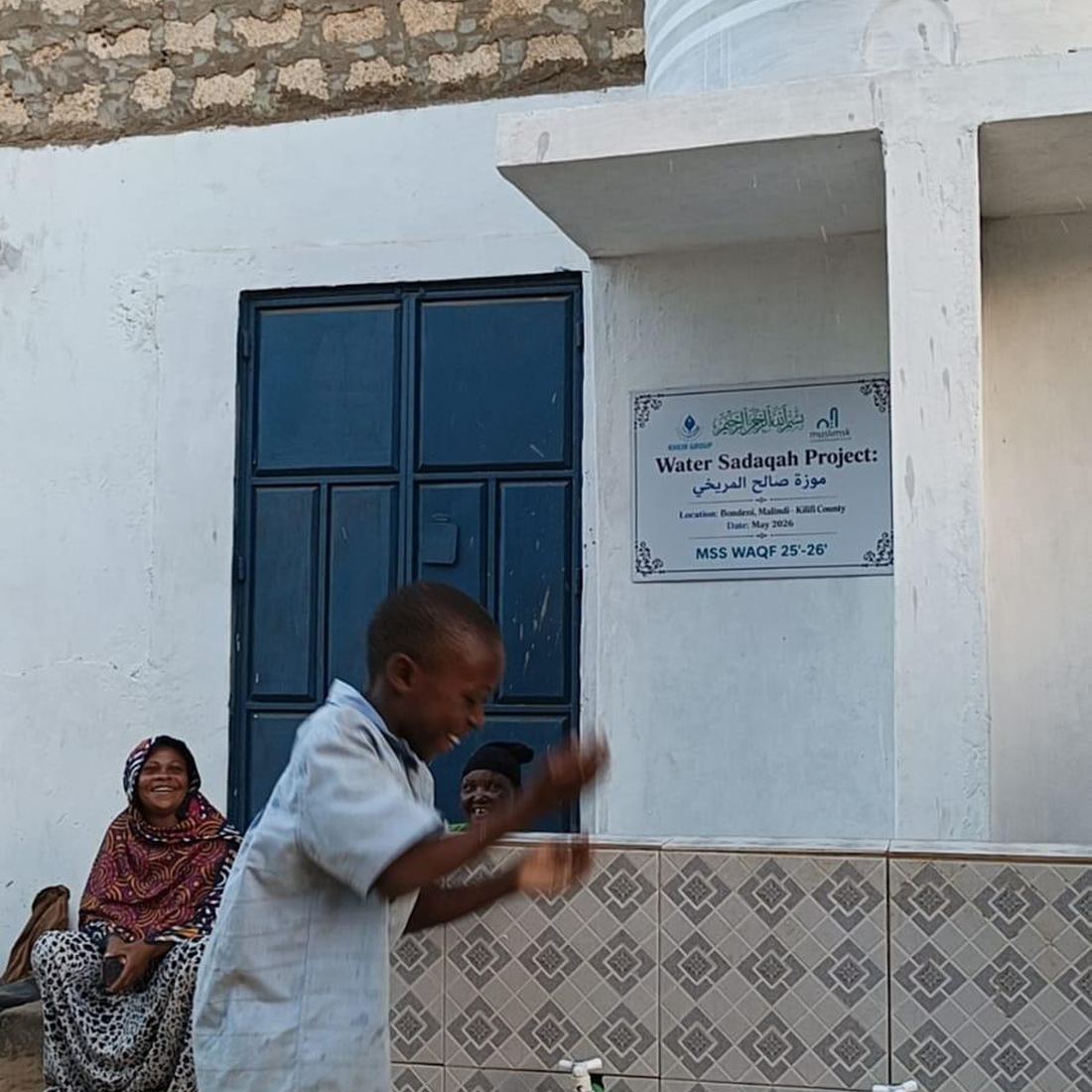 A boy laughing as he washes his hands at one of the new taps