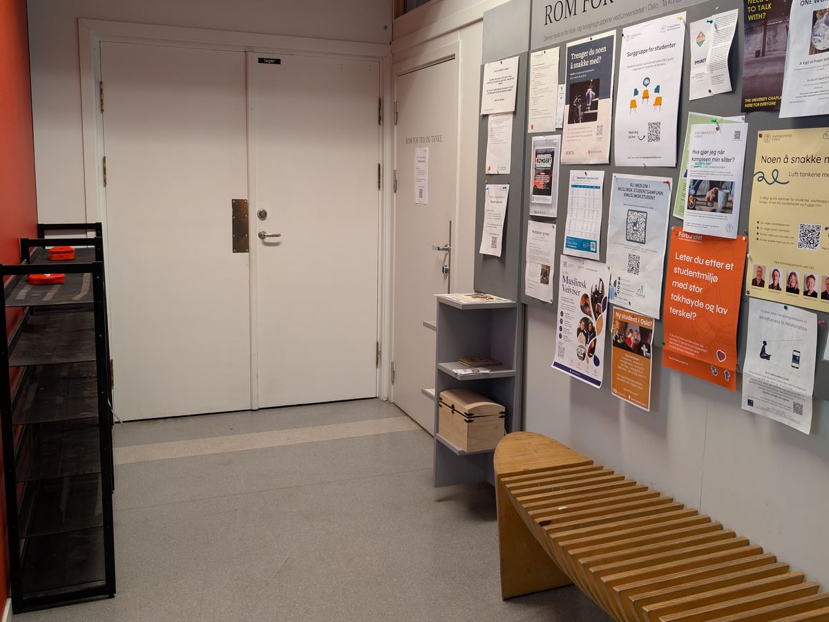 The door says Rom for tro og tanke. It is next to the noticeboard.